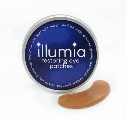 Illumia Restoring Eye Gel Patches in a tin container, showing the curved, serum-infused cooling gels for under-eye care designed for depuffing and treating dark circles.