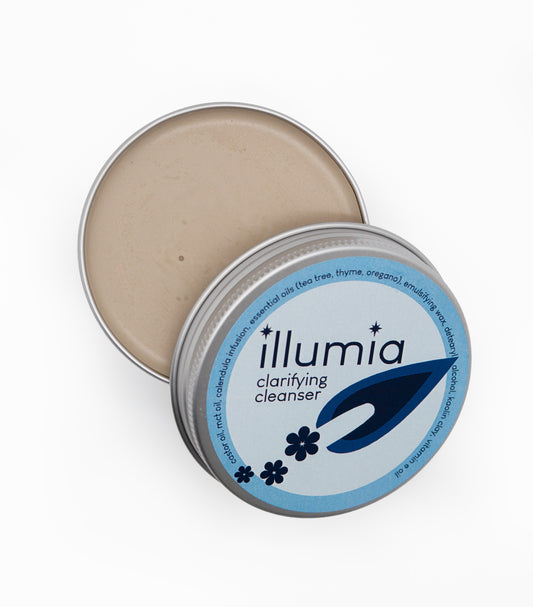 Open tin of Illumia Skincare Clarifying Cleanser showing the smooth, anhydrous balm texture for deep facial cleansing.